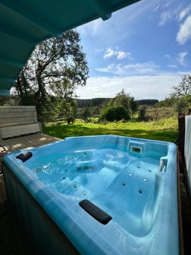 a hot tub on a patio with a view of a field at Glenariff Forest Pine Cabin in Glenariff