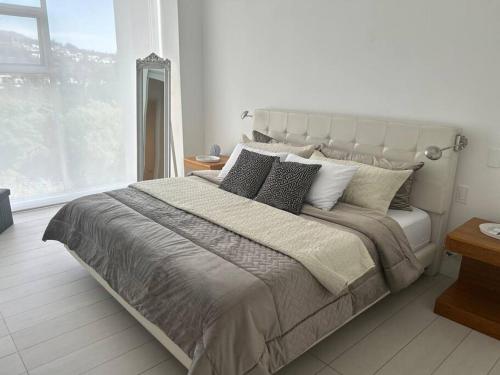 una camera bianca con un grande letto e una finestra di Alojamiento sin estrés de lujo a Quito