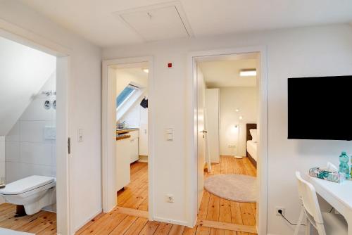 ein weißes Bad mit einem WC und einem TV in der Unterkunft Charmante Dachgeschosswohnung in Pforzheim