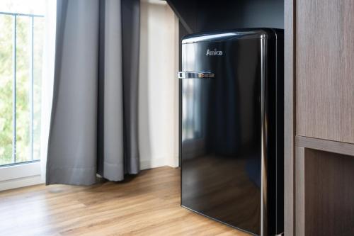 um frigorífico preto num quarto com uma janela em We rooms Hotel em Karben