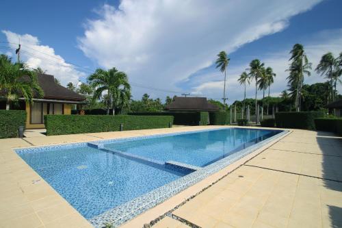 einen Pool in einem Garten mit Palmen in der Unterkunft Chaba Villa at Had Yao Beach in Had Yao Beach