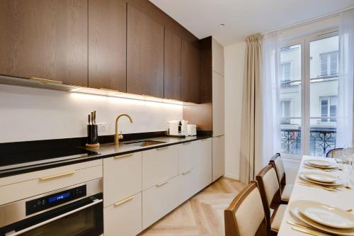 une cuisine avec des armoires blanches, une table et une fenêtre dans l'établissement Luxurious Apartment - 3BDR-8P - Bastille, à Paris
