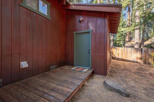 a red building with a green door and a wooden porch at Cozy Pet-Friendly Cabin w Fenced-In Yard Close to Slopes Beach Town in Carnelian Bay