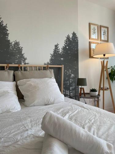 ein Schlafzimmer mit einem Bett mit weißer Bettwäsche und einer Lampe in der Unterkunft Charmant Studio avec parking - Confort Moderne in Bourges
