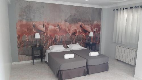 a bedroom with two beds and a painting on the wall at flamingos rio in Montijo