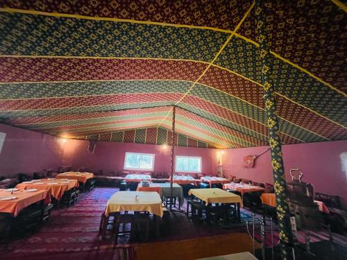 comedor con mesas y sillas y techo colorido en Riad Les Roches Todra, en Tinerhir