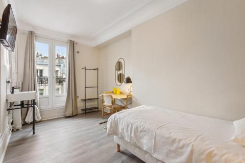 ein weißes Schlafzimmer mit einem Bett und einem Tisch in der Unterkunft Hôtel Juliette in Paris