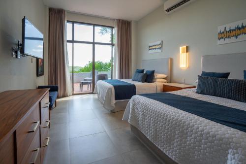 une chambre d'hôtel avec deux lits et une télévision à écran plat dans l'établissement Ocean Breath Villa at Villas Sol Resort, à Sardinal