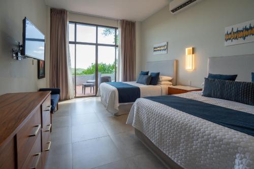 a hotel room with two beds and a flat screen tv at Ocean Breath Villa at Villas Sol Resort in Sardinal