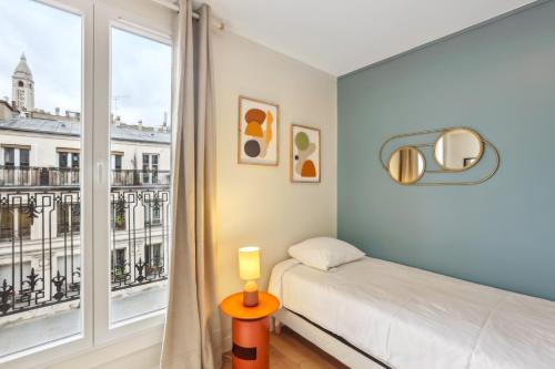 a bedroom with a bed and a large window at Hôtel Juliette in Paris