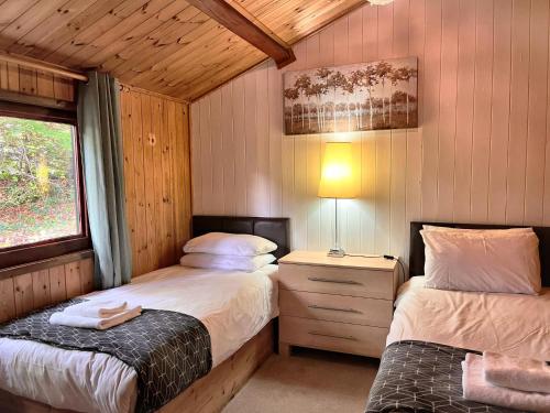 um quarto com 2 camas num chalé de madeira em Snowdrop 13-Hot Tub-Woodlandlodges-Carmarthenshire em Carmarthen