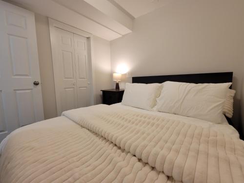 a bedroom with a large white bed with a black headboard at Walkout Basement Suite in Calgary
