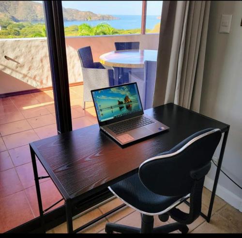 a laptop computer sitting on a desk with a chair at Cozy Resort Beach Condo in Playa Hermosa in Sardinal