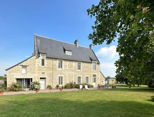 ein großes Steinhaus mit großem Hof in der Unterkunft Le Clos de Baron sur Odon, un havre de paix. in Baron-sur-Odon