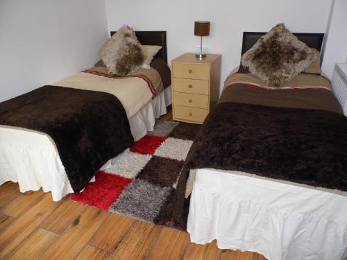 a bedroom with two beds and a wooden floor at Granary Cottages in Swindon