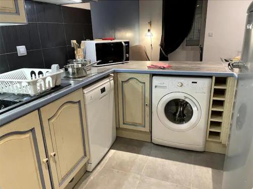 eine Küche mit einer Waschmaschine und einer Mikrowelle in der Unterkunft Appartement avec Parking Gratuit et Wifi in Vierzon