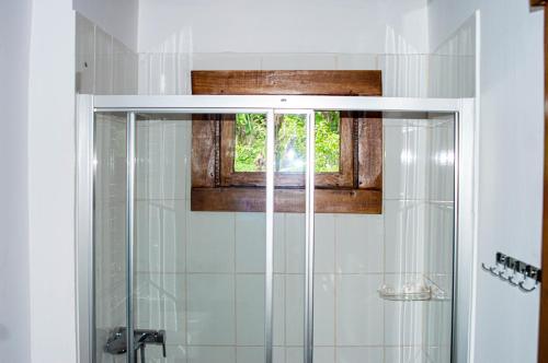 a bathroom with a glass shower with a window at ECO-POR in Rio do Ouro