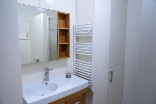 a white bathroom with a sink and a mirror at Escapade Annécienne in Annecy
