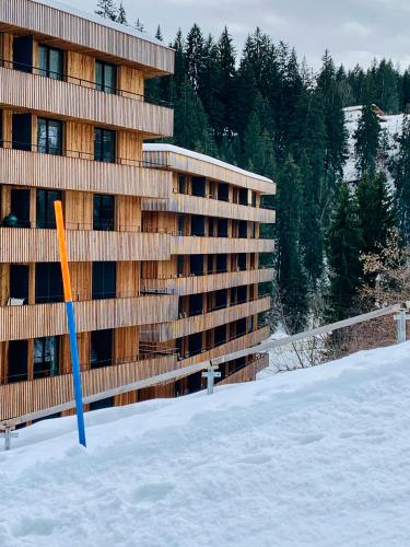 a building in the snow with a blue pole in the snow at Sunny Stenna Selva 3-room ski-in ski-out apartment right by the slopes & lifts in Flims