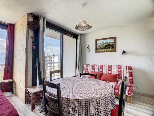 Cette chambre comprend une table, un canapé et une fenêtre. dans l'établissement Appartement rénové à 50m des pistes, balcon Est, 2 étoiles, 5 pers. - FR-1-417-24, à La Toussuire