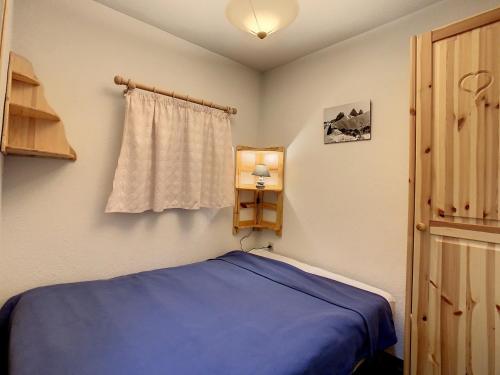 une chambre avec un lit bleu et une fenêtre dans l'établissement Appartement cosy 4 pers avec balcon sud à La Toussuire, proche commerces et pistes - FR-1-417-29, à La Toussuire