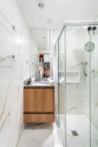 a bathroom with a sink and a glass shower at Studio Design Próx ao Metrô Brás com piscina in São Paulo