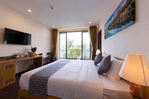 um quarto com uma cama grande e uma janela grande em Silk and Sea Hotel em Hoi An