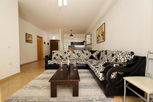 ein Wohnzimmer mit einem schwarzen Sofa und einem Tisch in der Unterkunft Noa Apartments in Vlorë