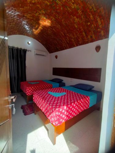a room with two beds with red sheets and a ceiling at Jamaica Guest House in Aswan