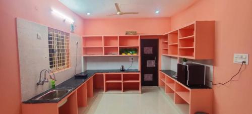 a kitchen with orange cabinets and a sink in a room at RUSHITHA HOME STAY-AC Rooms-FREE WIFI-FLAT TV- KITCHEN-DOOR SERVICE-NEAR TO ALIPIRI in Tirupati