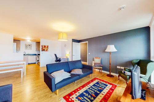 uma sala de estar com um sofá azul e uma cozinha em Appealing 2 Bedroom apartment in Bethnal Green em Londres