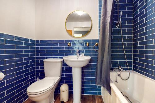 een blauw betegelde badkamer met een toilet en een wastafel bij Appealing 2 Bedroom apartment in Bethnal Green in Londen