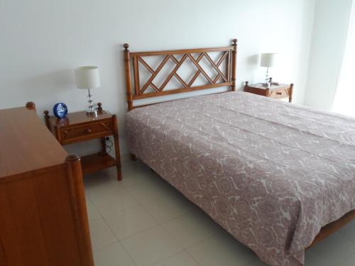 ein Schlafzimmer mit einem Bett und zwei Nachttischen in der Unterkunft Apartamento Varandas do Sol Nascente in Porches
