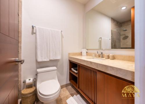 ein Badezimmer mit Toilette, Waschbecken und Spiegel in der Unterkunft NHOA 209B Lux 1BR Condo Pool View in Aldea Zama in Tulum