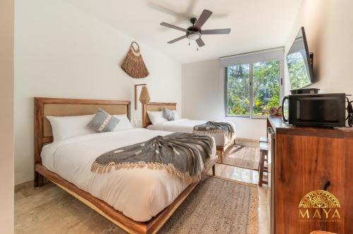 ein Schlafzimmer mit zwei Betten und einem Fernseher und einem Fenster in der Unterkunft NHOA 209A Lux 2BR Condo Pool View in Aldea Zama in Tulum