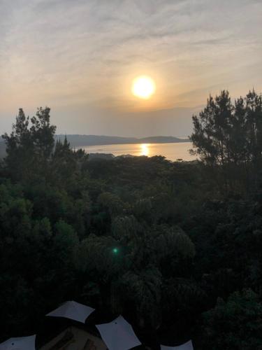 a sunset over a body of water with trees at The Address Resort in Kalangala