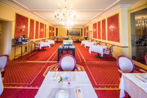 a restaurant with tables and chairs and a chandelier at Mercure Moulins Centre Hôtel de Paris in Moulins