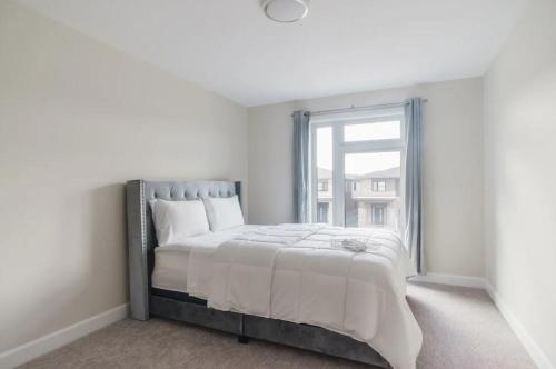 a white bedroom with a large bed with a window at Niagara Elite Enclave in Niagara Falls