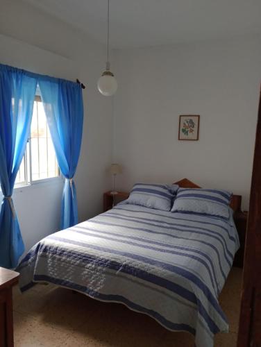 1 dormitorio con 1 cama con cortinas azules y ventana en Vivienda en altos con uso exclusivo de entrada de auto y parrilla en Miramar