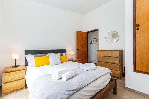 ein Schlafzimmer mit einem großen weißen Bett mit gelben Kissen in der Unterkunft Casa Gaivota by Algarve Golden Properties in Lagos