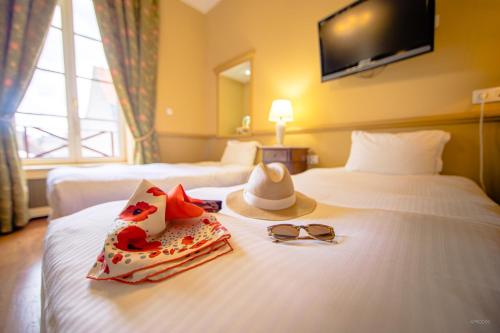 a hotel room with two beds and a hat and sunglasses at Mercure Moulins Centre Hôtel de Paris in Moulins