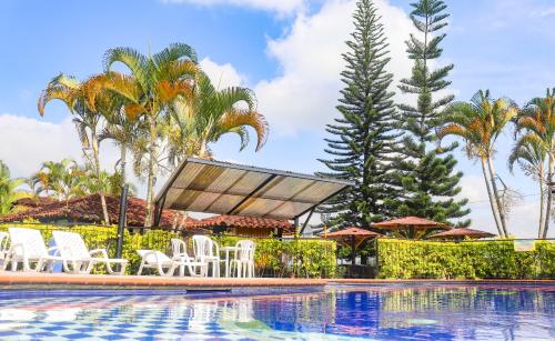 a pool at a resort with chairs and umbrellas at Hotel Quindio Campestre in Montenegro