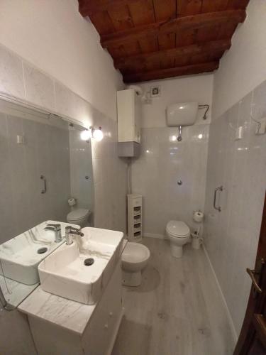 Baño blanco con lavabo y aseo en La Bellana, en Guardistallo