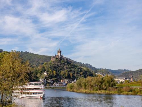 ein Boot auf einem Fluss mit einem Schloss auf einem Hügel in der Unterkunft Fata Morgana in Cochem