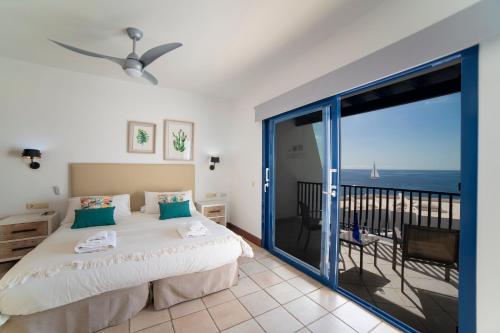 a bedroom with a bed and a balcony with the ocean at Jasmin in Puerto Calero