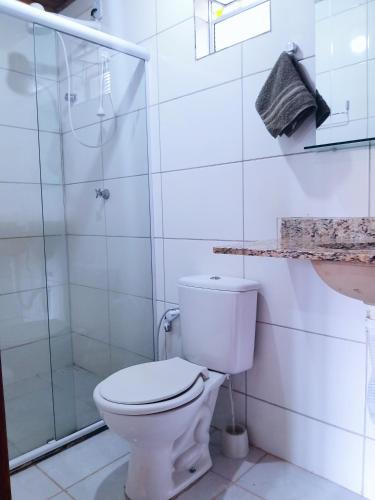 a white bathroom with a toilet and a shower at Casa Relva Suítes in Lençóis