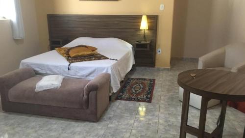 ein Schlafzimmer mit einem Bett, einem Stuhl und einem Tisch in der Unterkunft HOTEL VEREDAS in Monsenhor Paulo