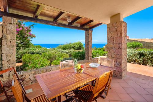 a wooden table on a patio with a view of the ocean at Villa Vittoria - Costa Paradiso in Costa Paradiso