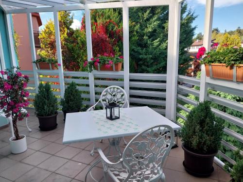a white table and chairs on a porch with potted plants at Cozy rooms in wine town - Modra in Modra