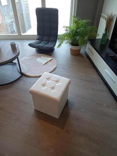 a living room with a white ottoman on the floor at Ap Dúplex en Casco Histórico in Ourense